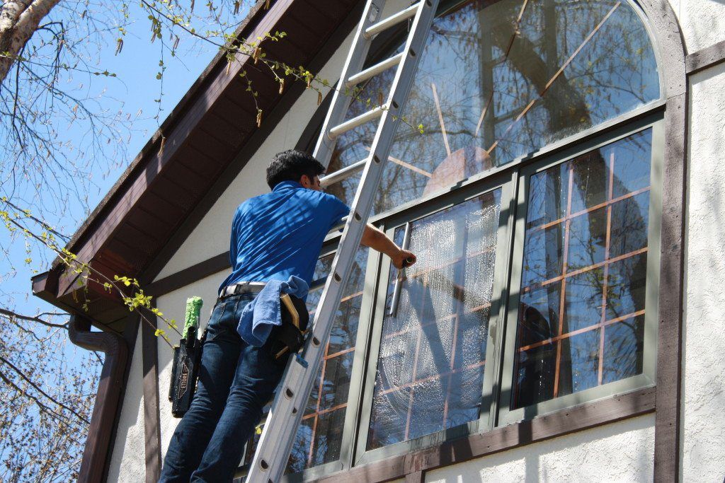 Man on ladder cleaning residential window